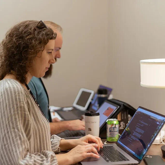 Two colleagues working side by side on laptops